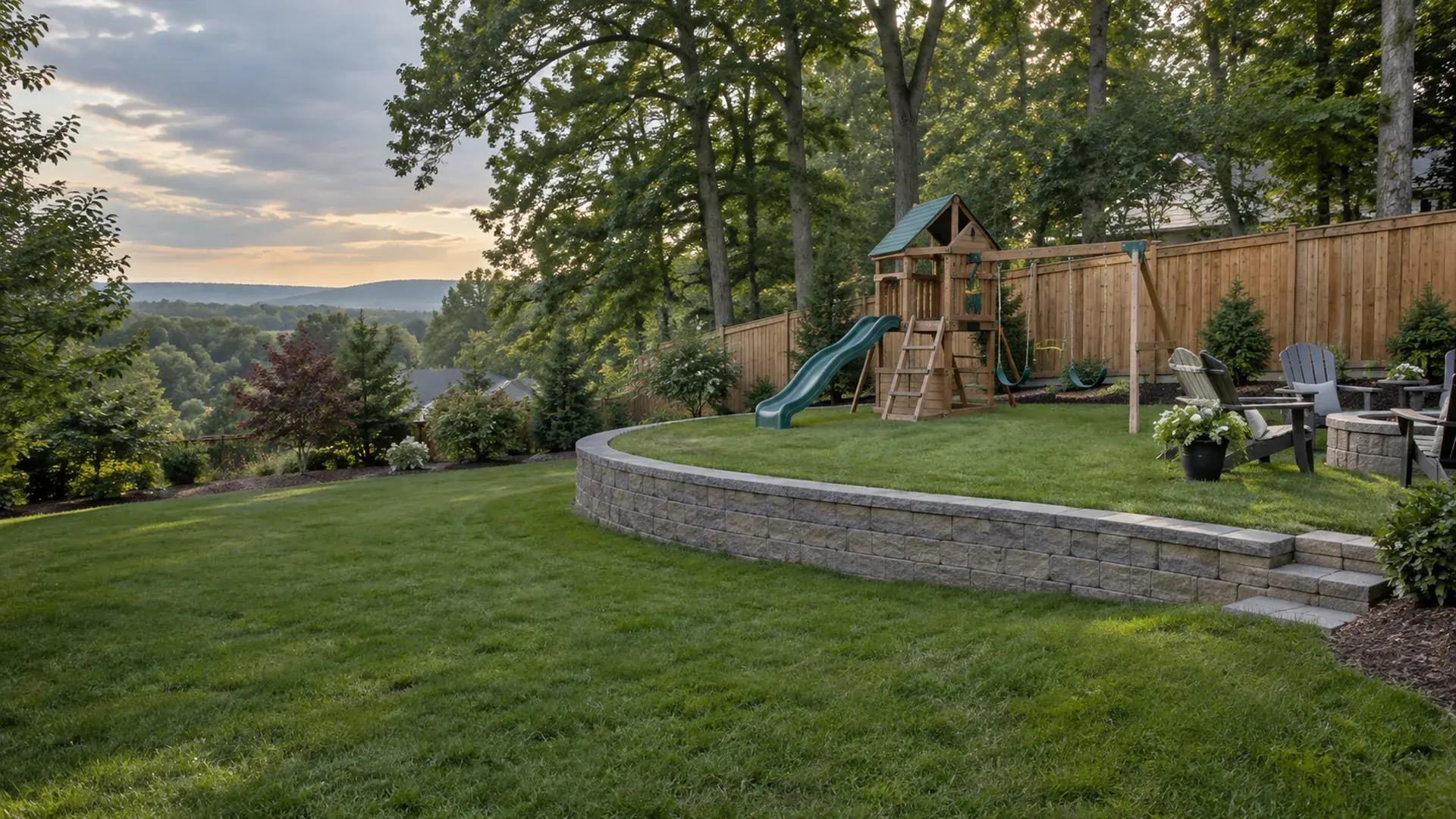 A level backyard lawn created by a low curved retaining wall, a swing set and patio chairs on the new flat ground, wooden privacy fence behind.