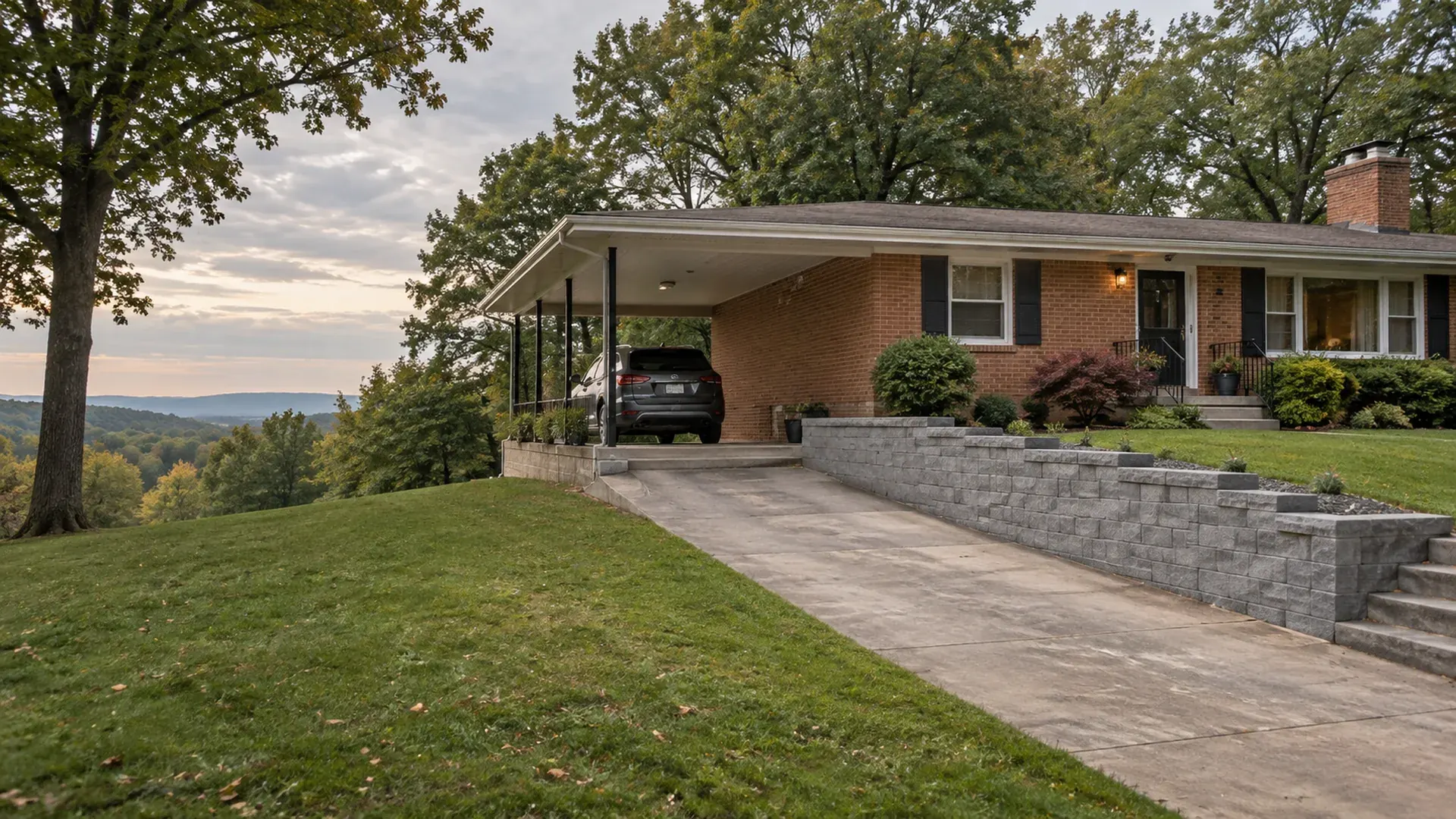 A mid-century ranch home in Dumbarton, Virginia with a new block retaining wall along a carport and driveway cut into a gentle slope.