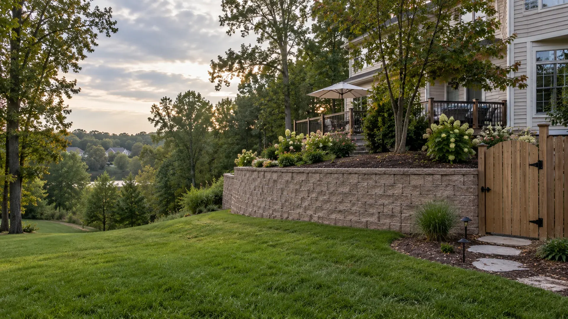 A rolling suburban backyard in Laurel, Henrico County, Virginia with a moderate-height block retaining wall and a narrow side-yard gate. A rolling suburban backyard in Laurel, Henrico County, Virginia with a moderate-height block retaining wall and a narrow side-yard gate.