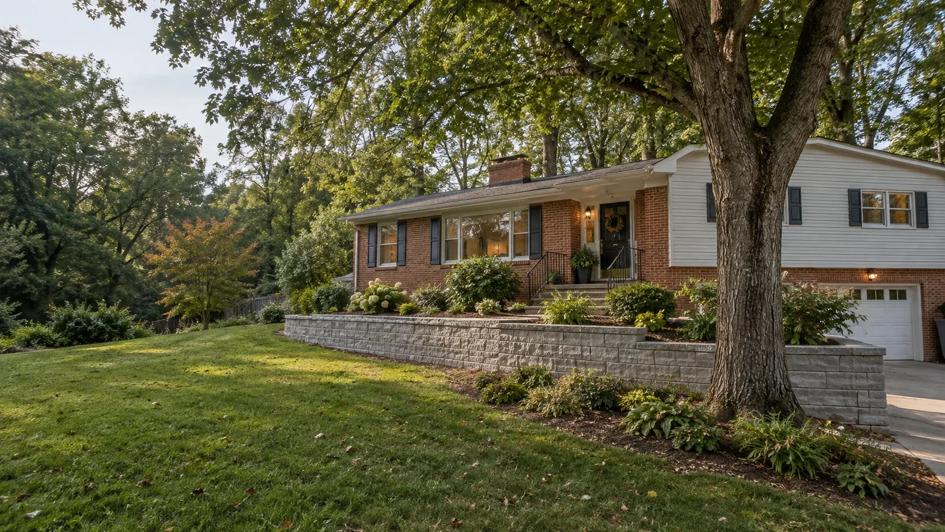 An established mid-century home in Tuckahoe, Virginia under a mature tree canopy with a new block retaining wall replacing an old timber wall. An established mid-century home in Tuckahoe, Virginia under a mature tree canopy with a new block retaining wall replacing an old timber wall.